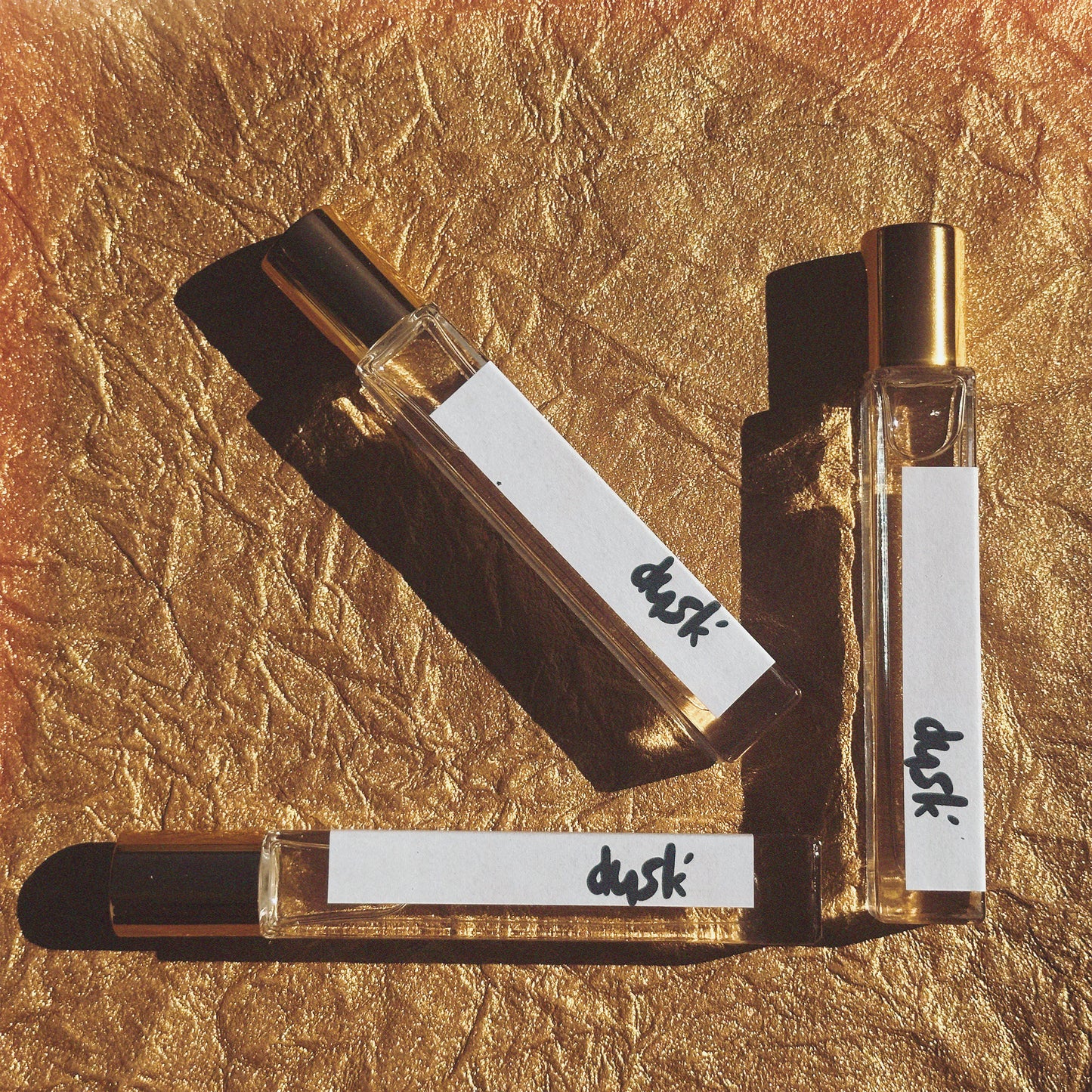perfume travel size roll on bottles against a stunning gold background