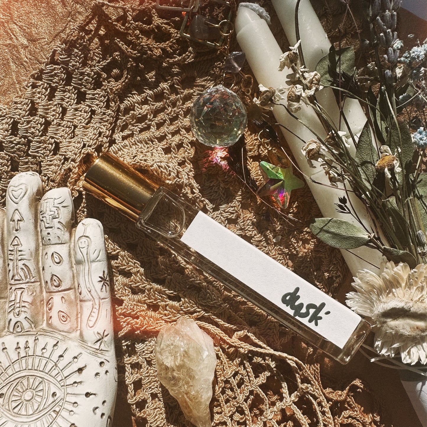 Perfume bottle on silk cloth surrounded by dried flowers and healing crystals