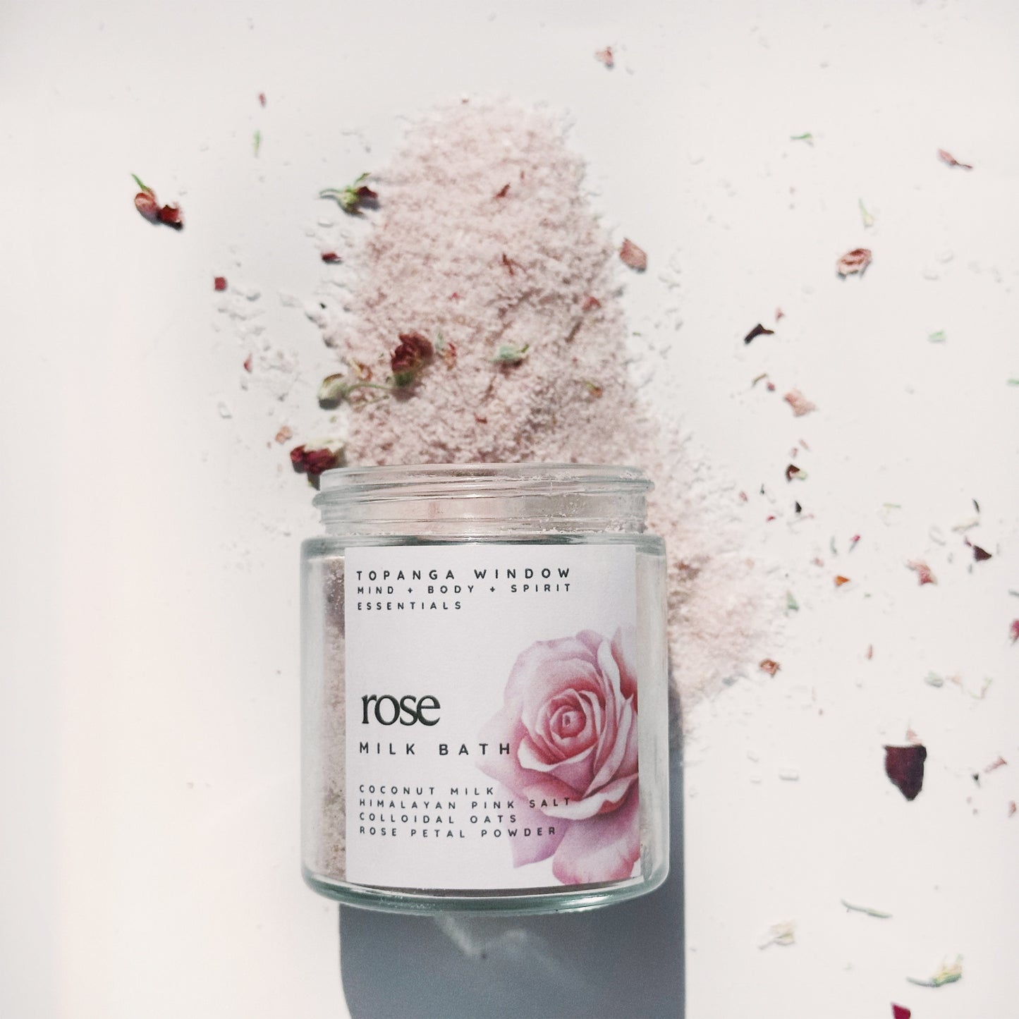glass jar with rose bath salts pouring out