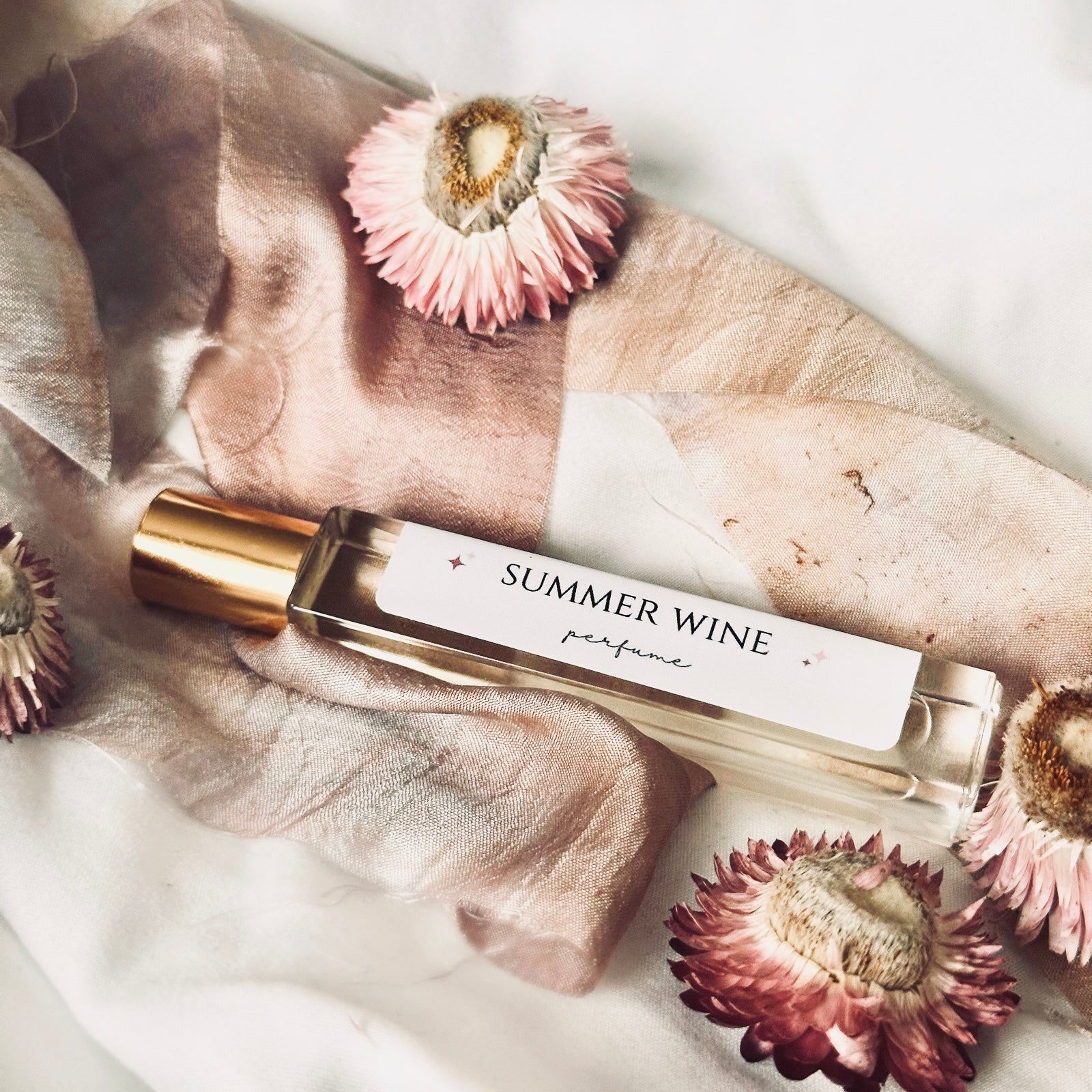 perfume bottle on silk cloth with surrounding dried pink  flowers