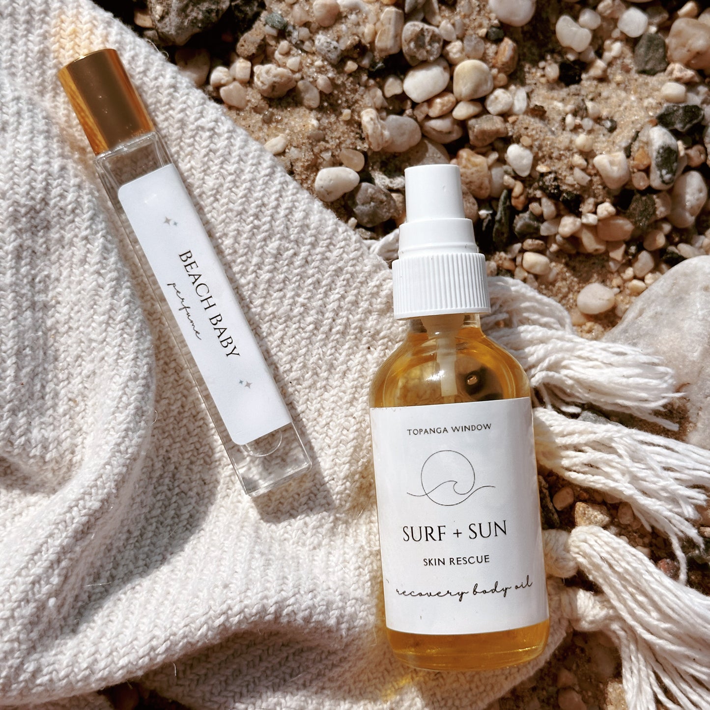 Body oil spray bottle and perfume roll on on a beach blanket in Malibu