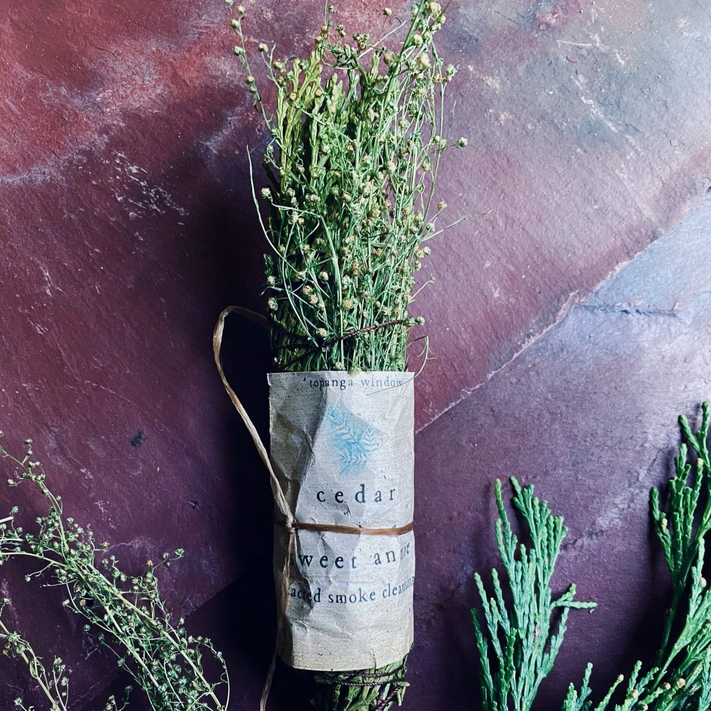 CEDAR STICK MADE WITH SWEET ANNIE. BUNDLED TOGETHER WITH A WHITE PAPER LABEL AND BROWN ORGANIC THREAD. uSED TO CLEANSE ENERGY IN SACRED SPACES OR YOUR HOME.