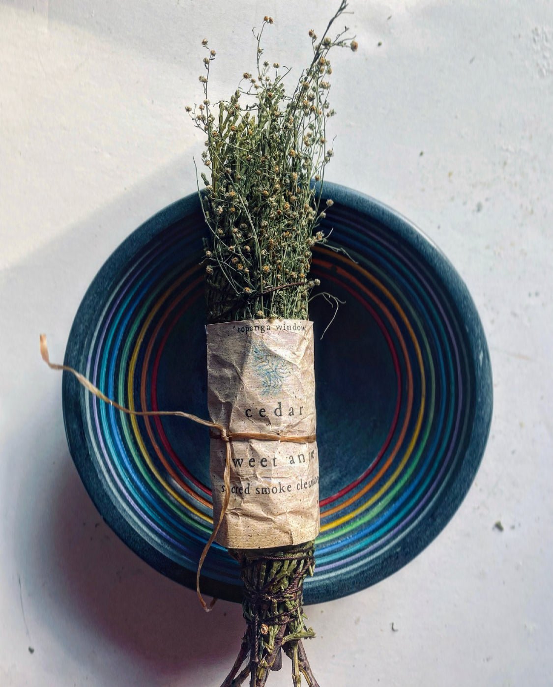SACRED SMOKE CLEANSING STICK IN A RAINBOW BOWL.