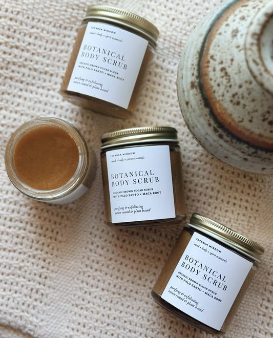 Three jars of Botanical Body Scrub on a textured surface