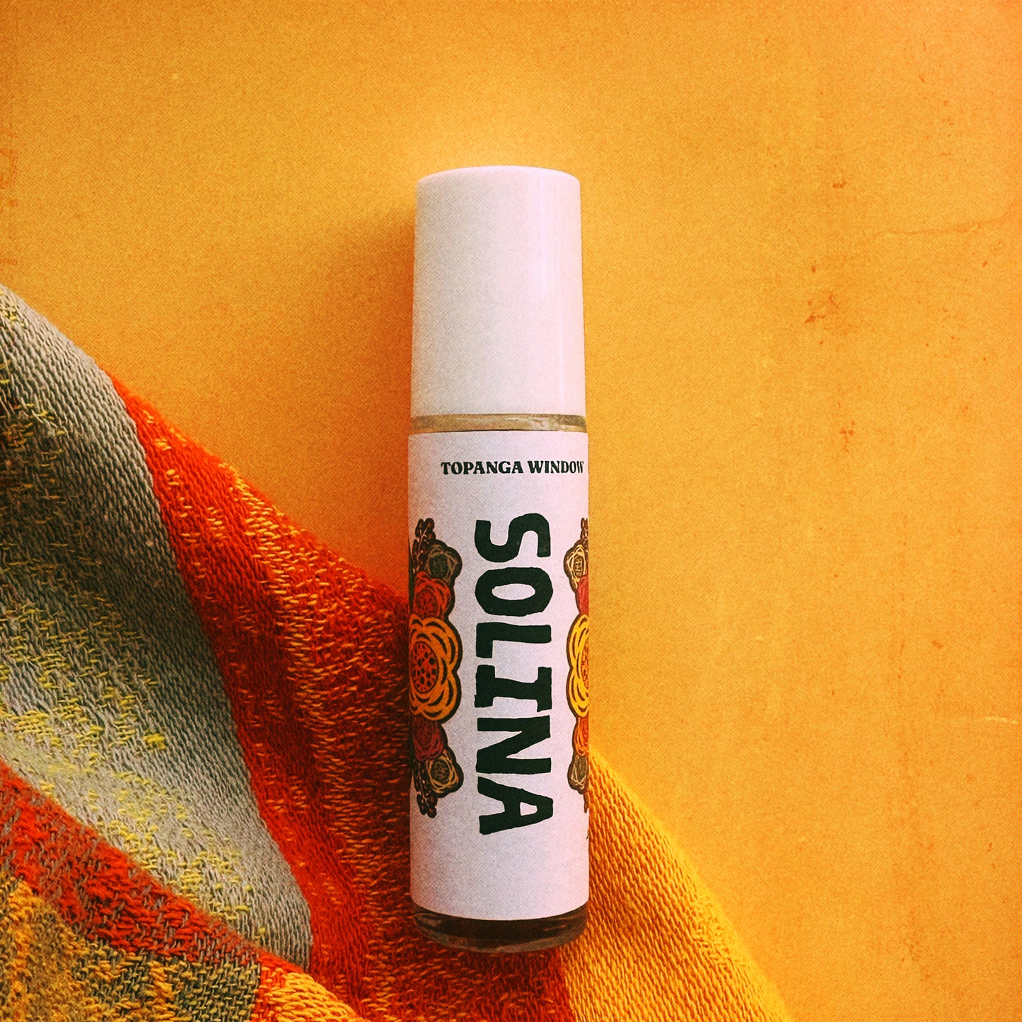 Roll-on bottle labeled 'SOLINA' on a textured orange surface
