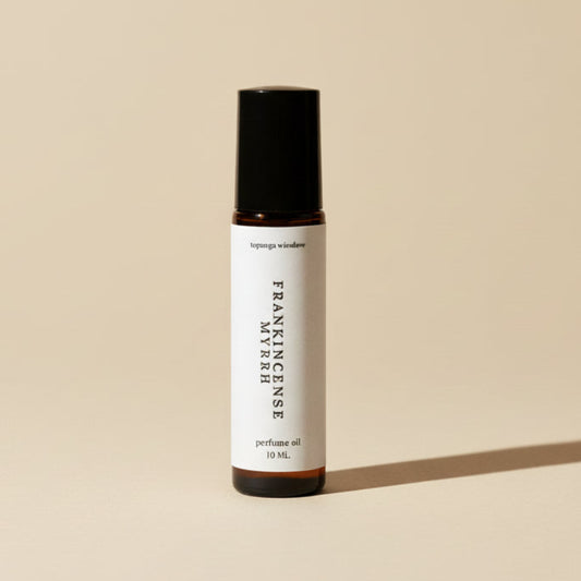 Perfume oil bottle labeled 'Frankincense Myrrh' on a textured beige background