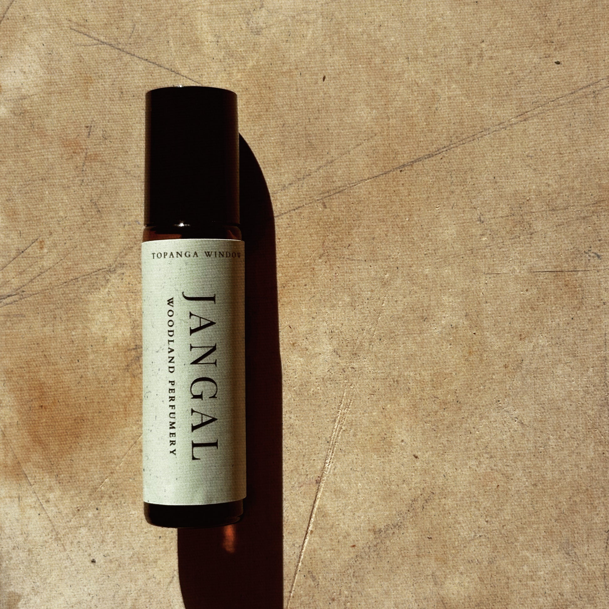 Bottle of Jangal perfume on a textured brown background