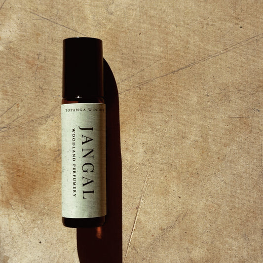 Bottle of Jangal perfume on a textured brown background