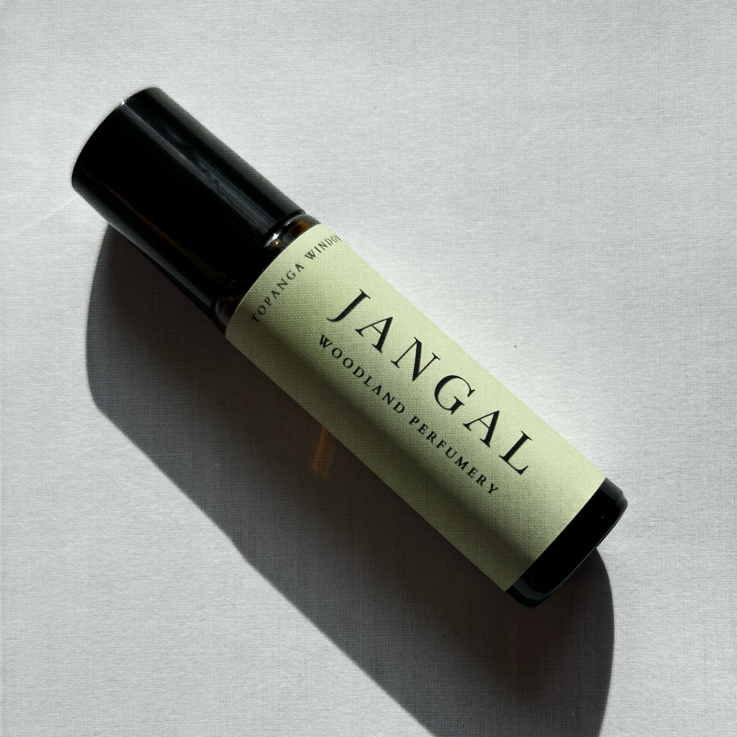 Roll-on perfume bottle labeled 'Jangal' by Woodland Perfumery on a light gray background