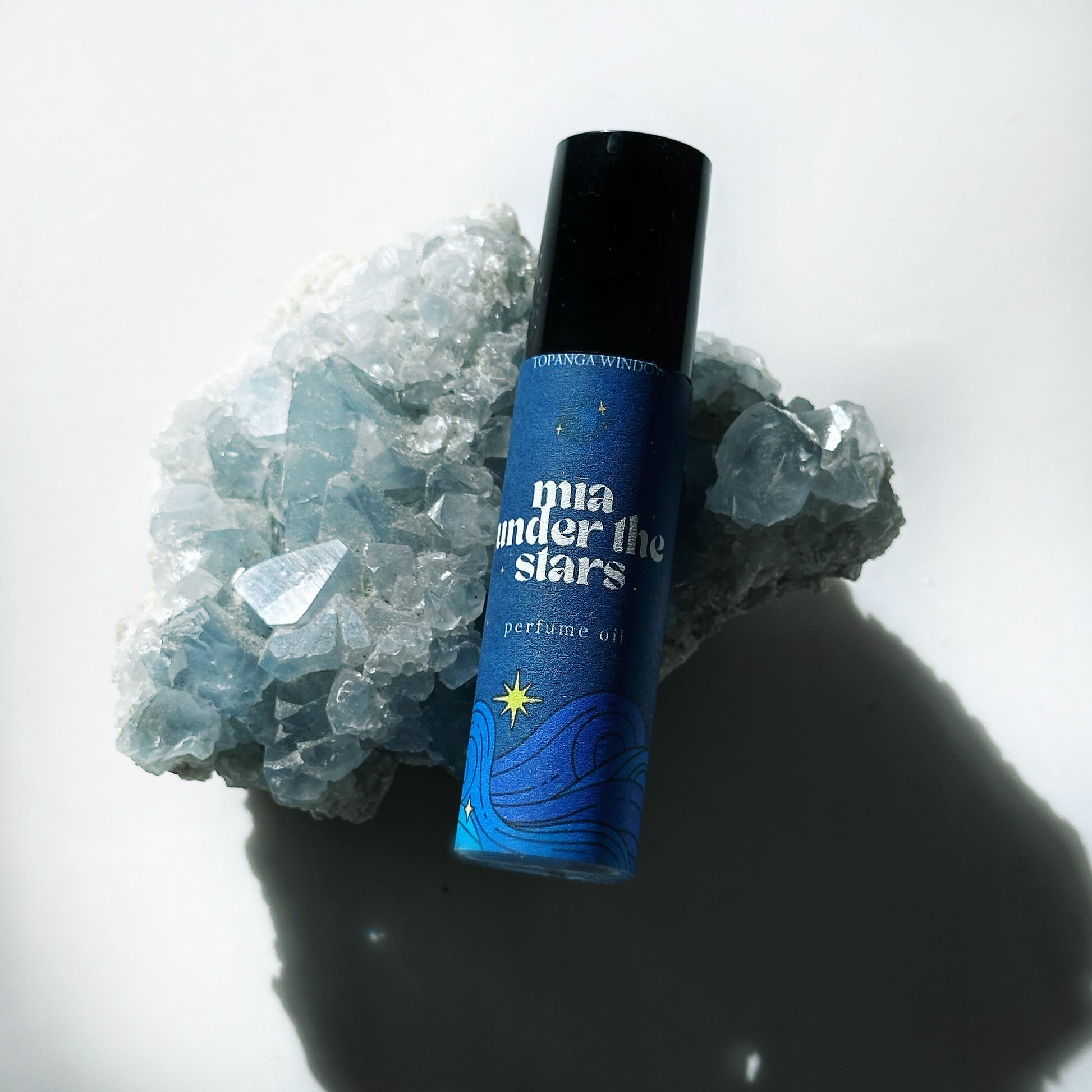 Perfume bottle labeled 'mia under the stars' on a white background with crystals.