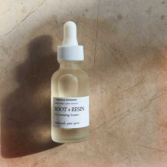 Bottle of 'Root + Resin' essence with a label on a textured surface