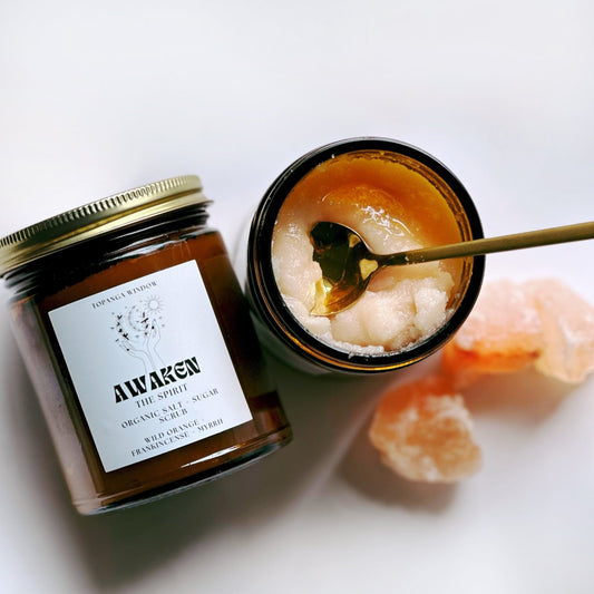 Glass amber jar with natural salt and sugar scrub. brass spoon in jar showing scrub and healing stone