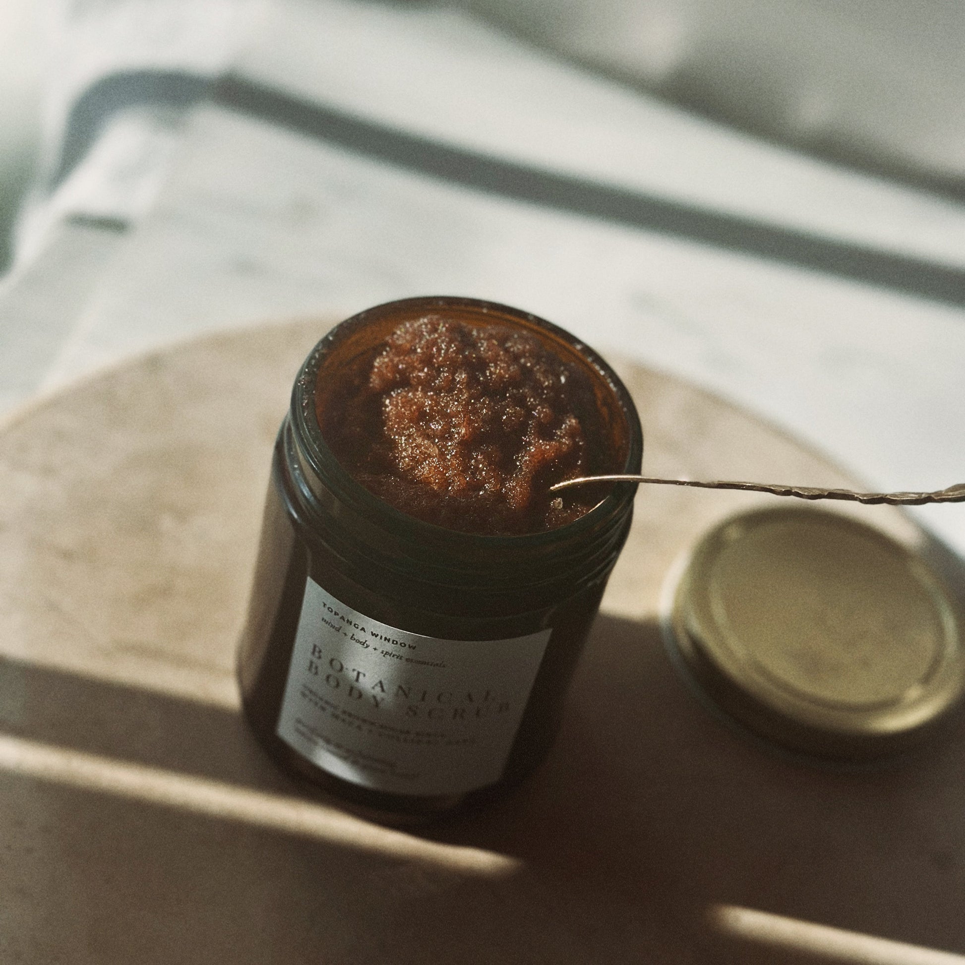 Jar of coffee scrub with a label on a light surface