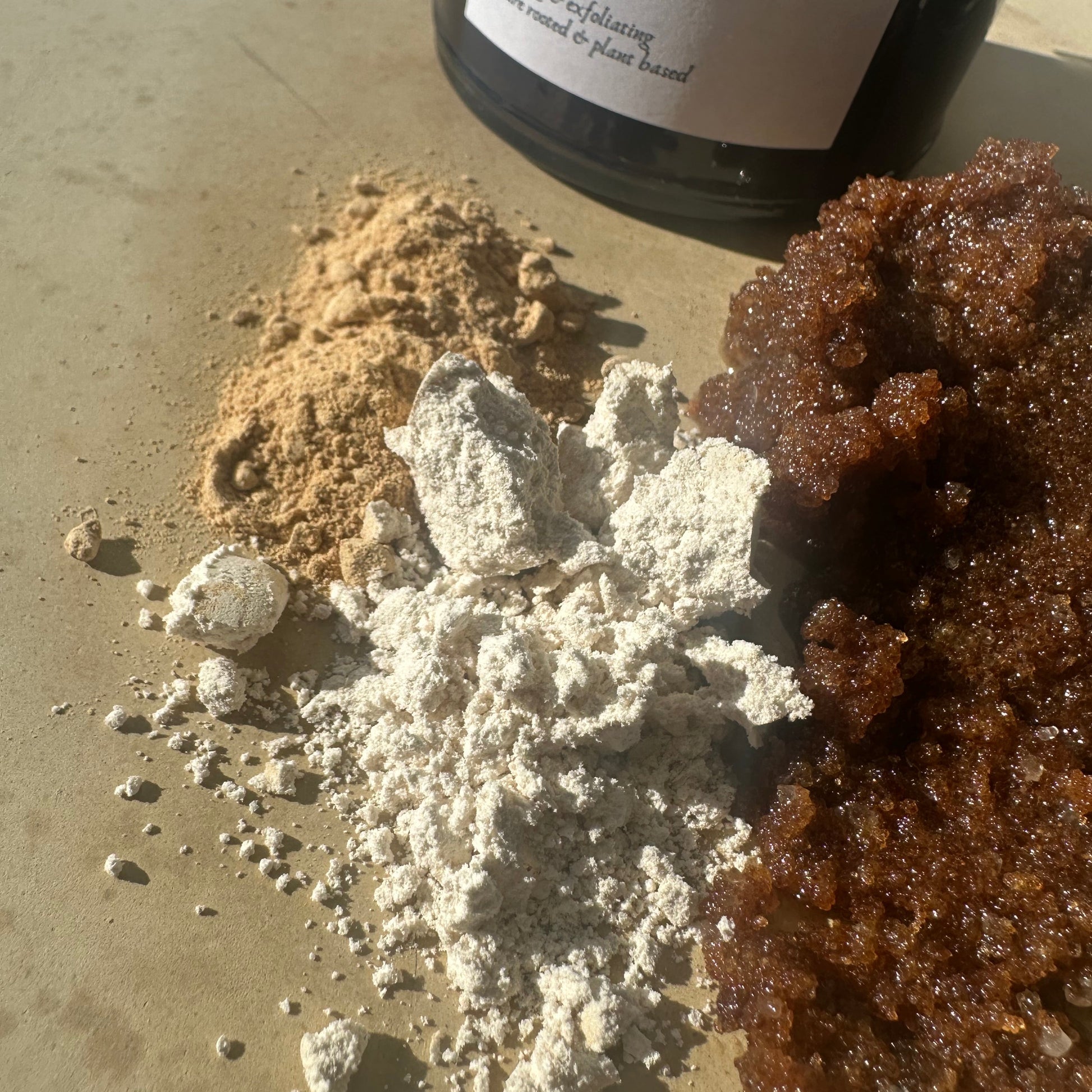 Body scrub with a bottle labeled 'Botanical Scrub' on a textured surface.