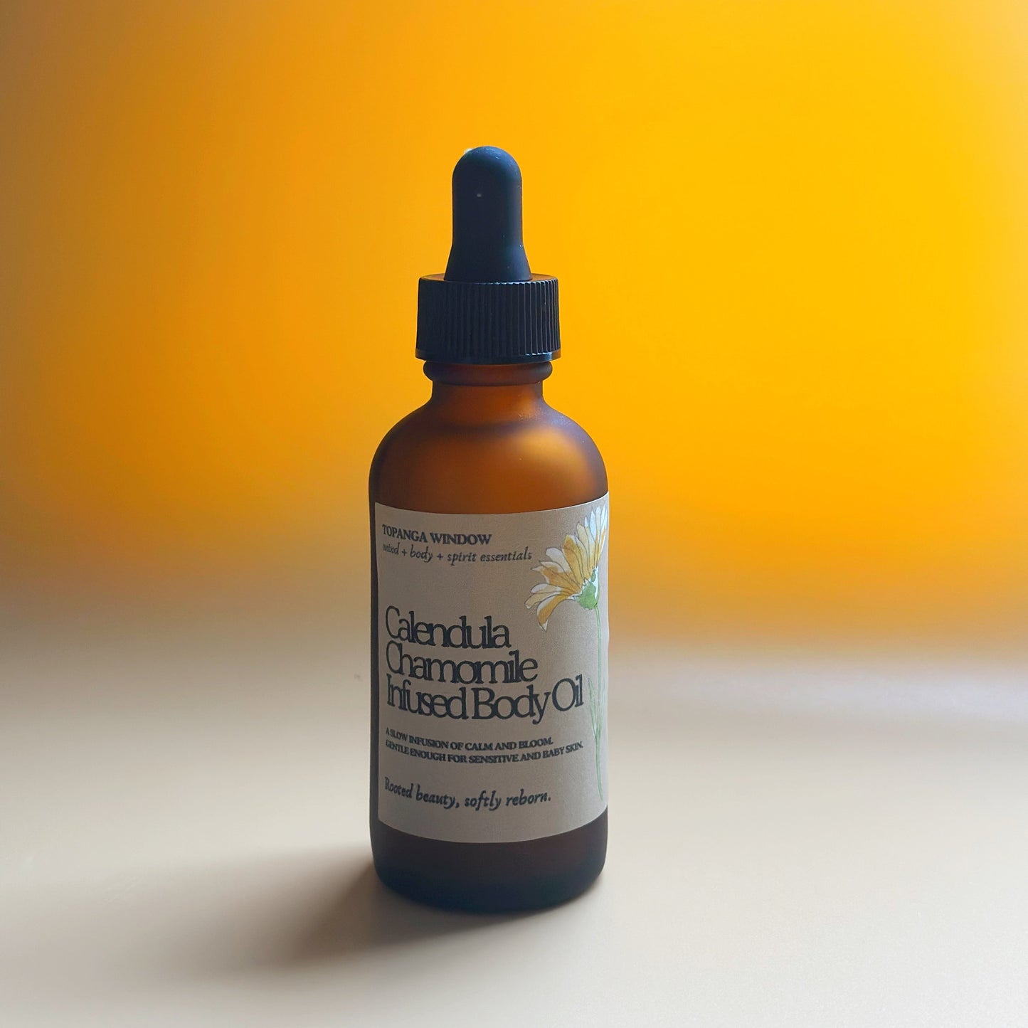 Bottle of Calendula Chamomile Infused Body Oil with a dropper on a gradient orange background