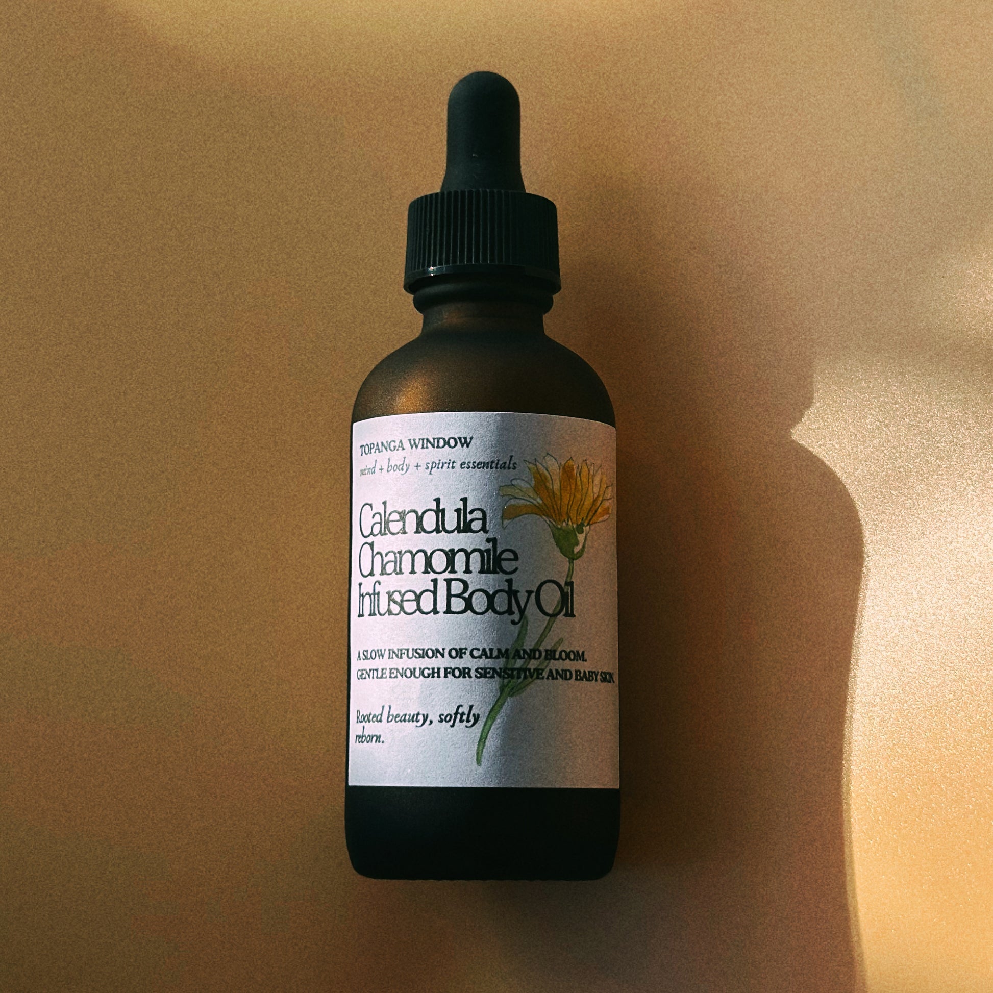Bottle of Calendula Chamomile Infused Body Oil with a dropper on a beige background