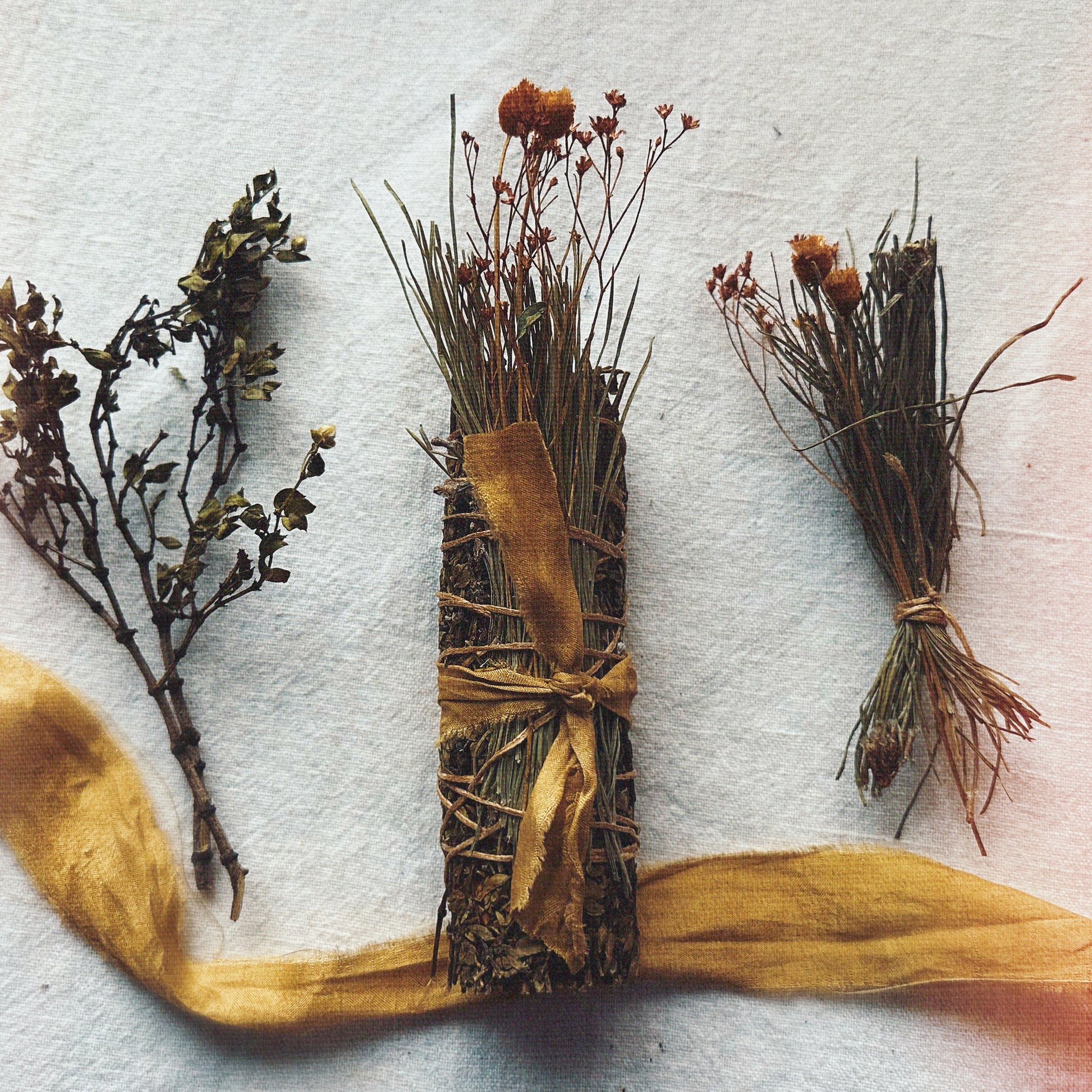 creosote smoke cleansing stick and a yellow ribbon on a textured white background