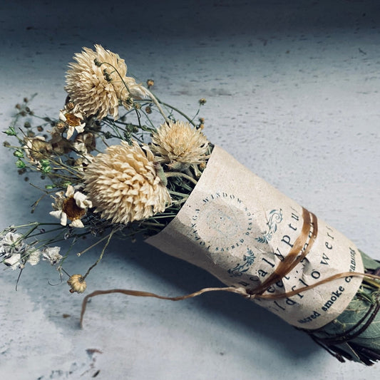Dried flowers wrapped in paper with a decorative band on a textured surface
