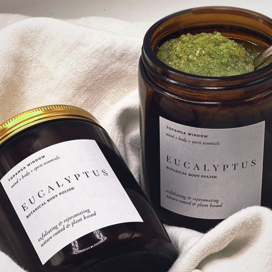 Two jars of Eucalyptus botanical body polish on a light fabric background