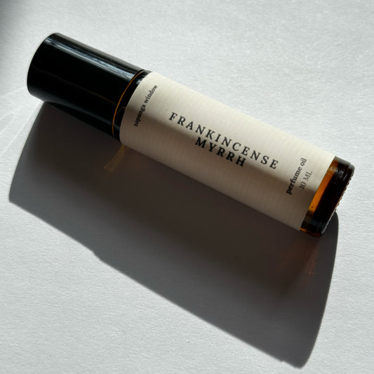 Roll-on bottle of Frankincense Myrrh perfume on a light background