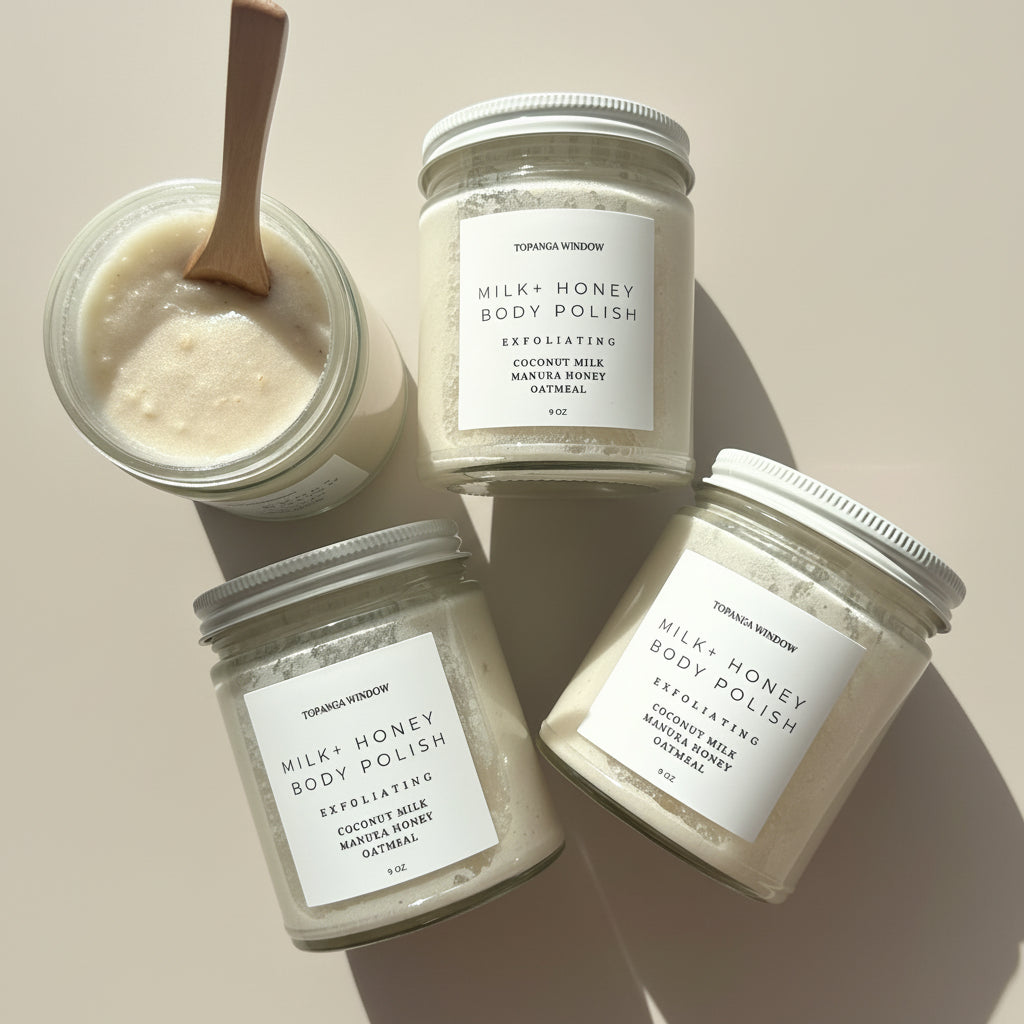 Jars of Milk + Honey body polish on a marble surface