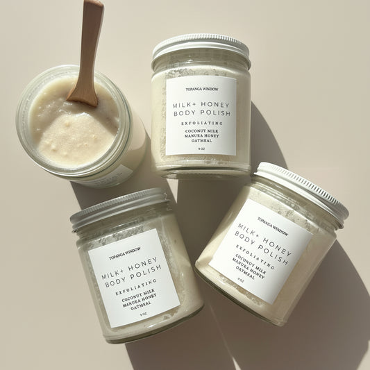 Jars of Milk + Honey body polish on a marble surface