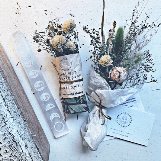 Decorative items including a book, candles, and dried flowers on a textured surface.