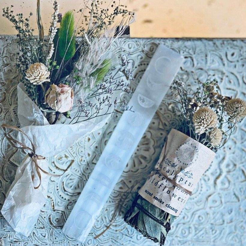 Decorative box with dried flowers, a glass tube, and a small book on a textured surface.