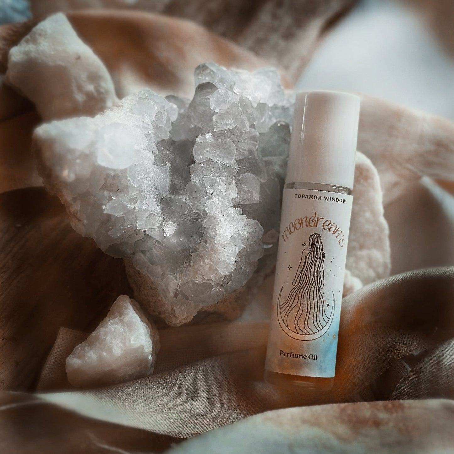 Perfume oil bottle with crystal rock on a soft fabric background