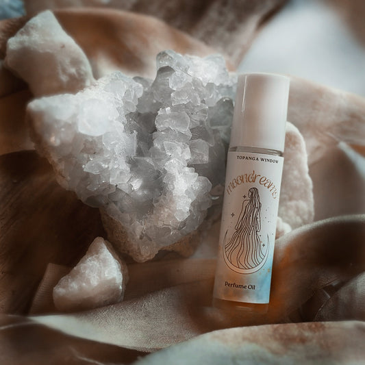 Perfume oil bottle with crystal rock on a soft fabric background