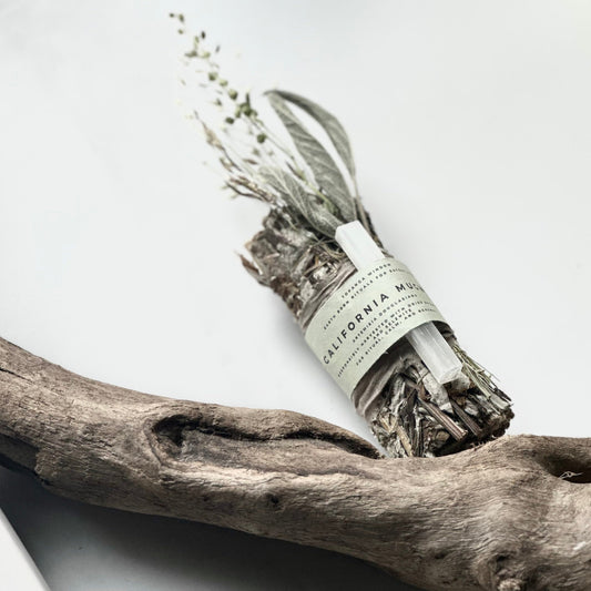 smudge stick on a piece of driftwood against a white background