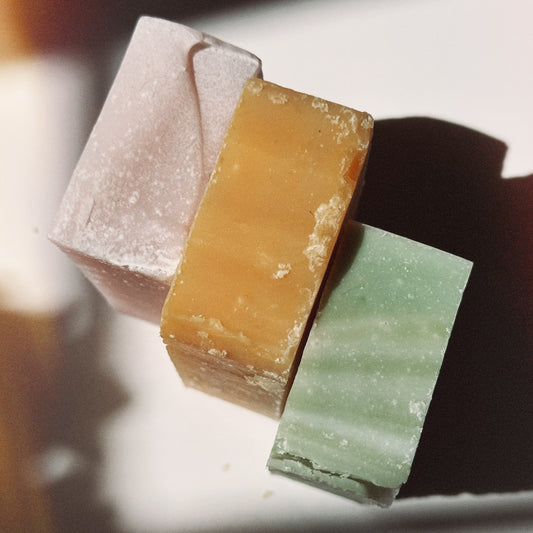 Three bars of soap in different colors on a white surface