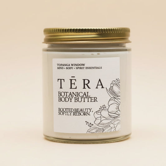 Téra botanical body butter jar with a gold lid on a textured white background