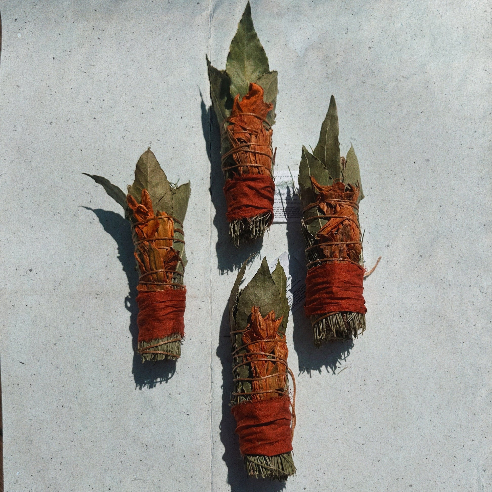 Four woven sticks with red and green materials on a gray surface