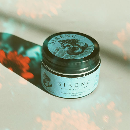 Sireène solid perfume jar with mermaid design on a blurred background