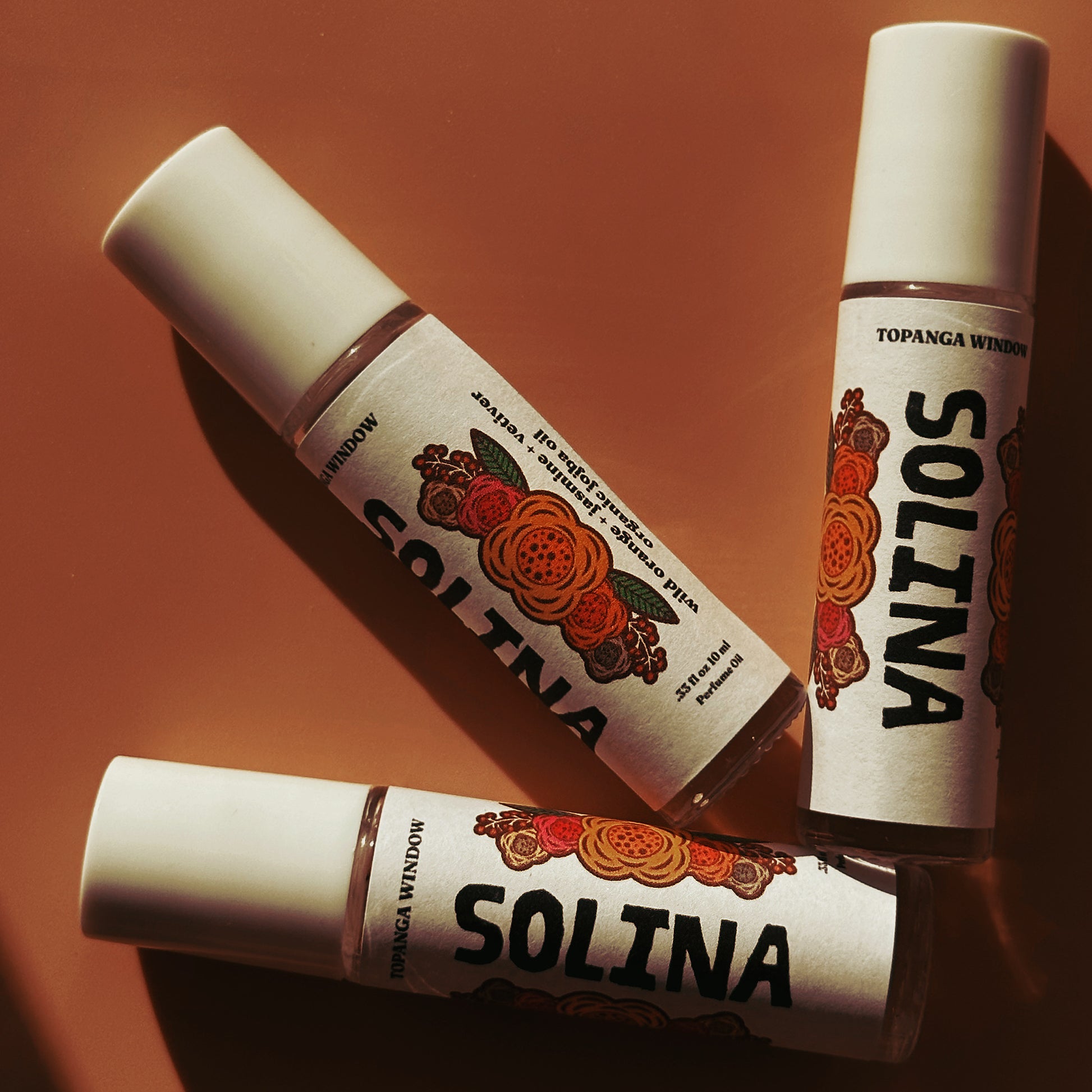 Three Solina perfume bottles on a brown background