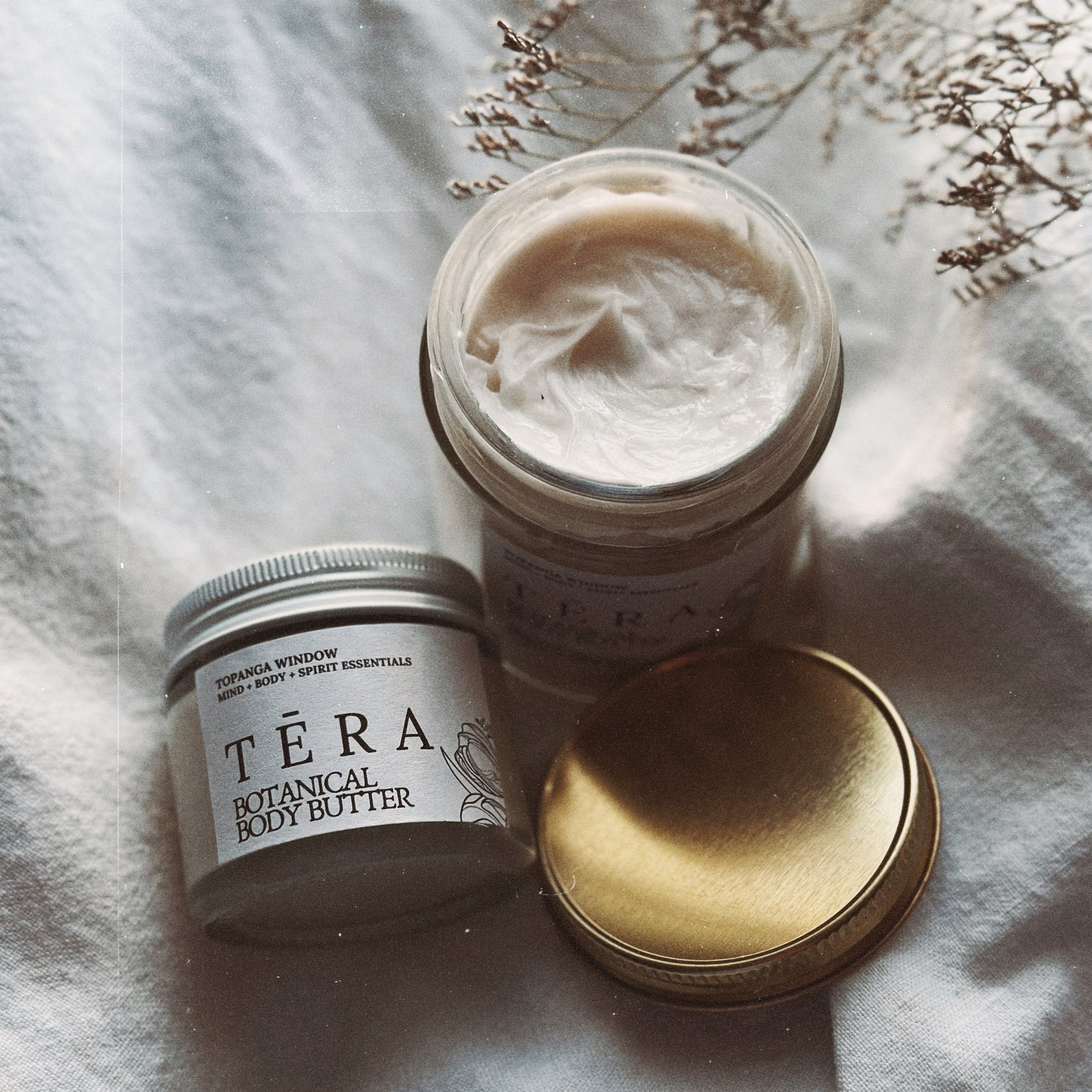 Téra botanical body butter jar with lid on a soft fabric background