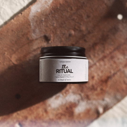 Jar of 'The Ritual' solid perfume on a textured surface