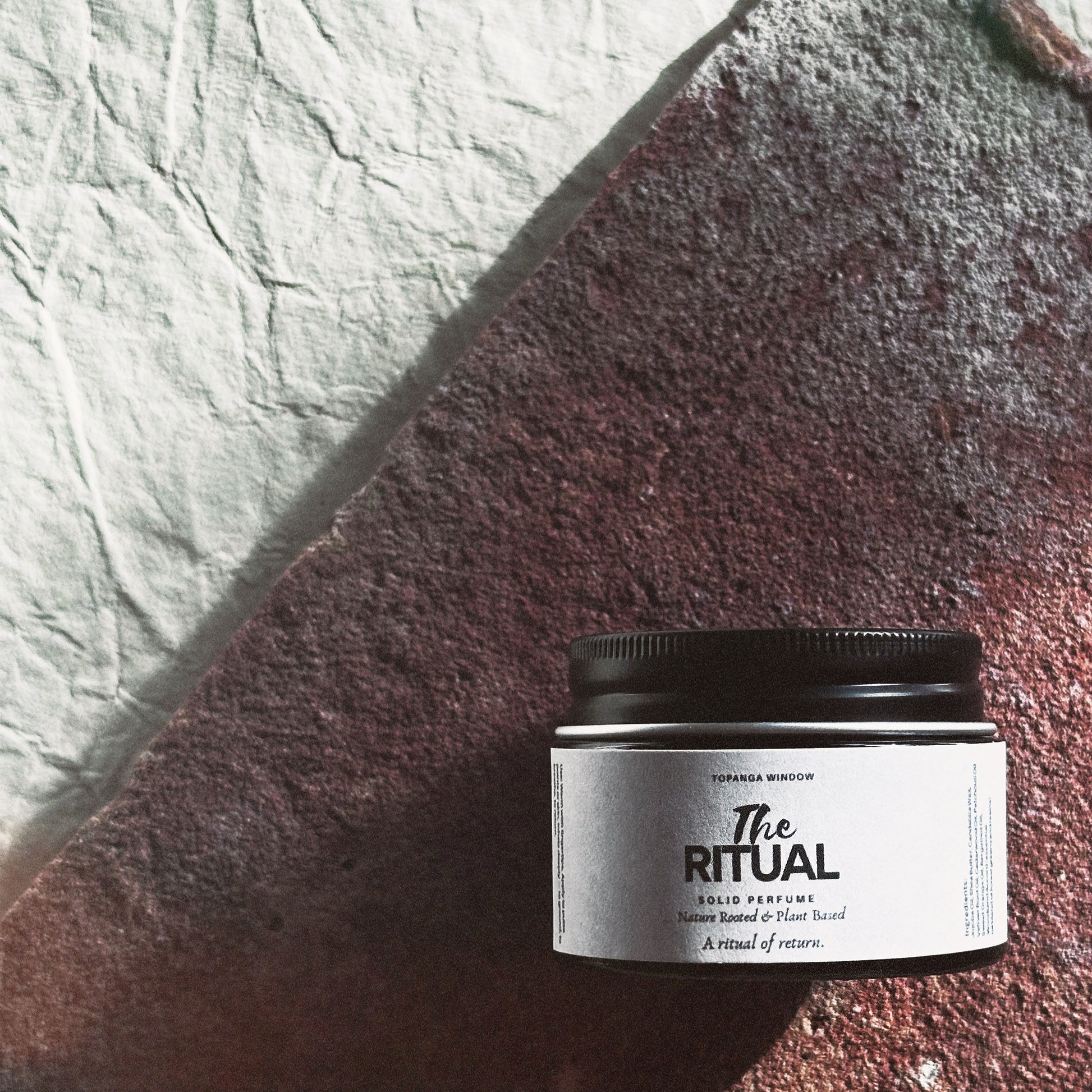 Jar of 'The Ritual' solid perfume on a textured surface