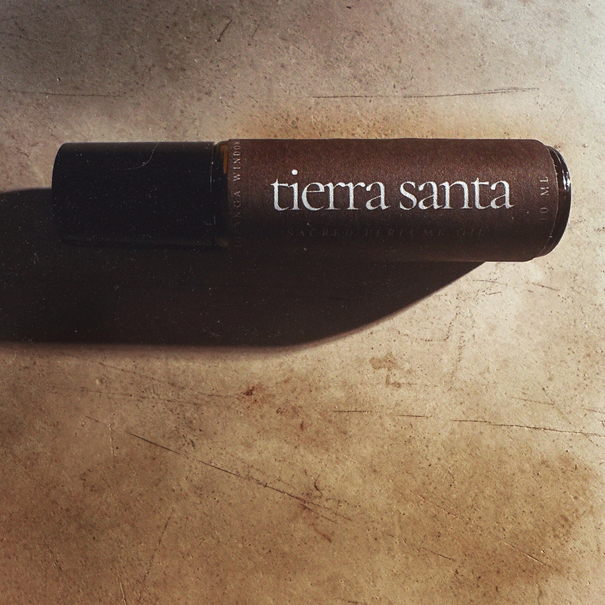 Tierra Santa perfume bottle on a rustic stone surface