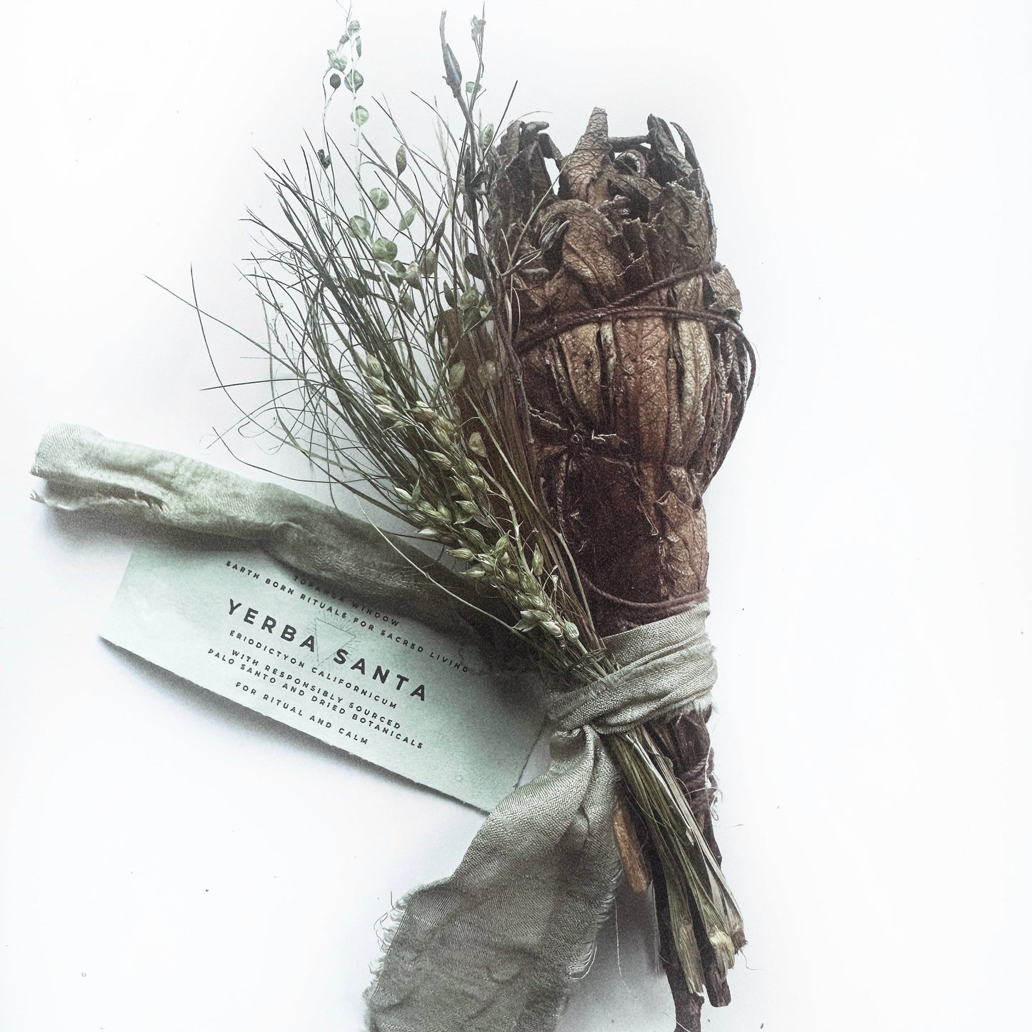 Smudge stick with herbs and a label on a white background