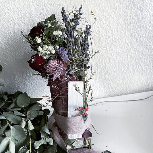 Bouquet of flowers in a vase on a white surface with a textured white wall background