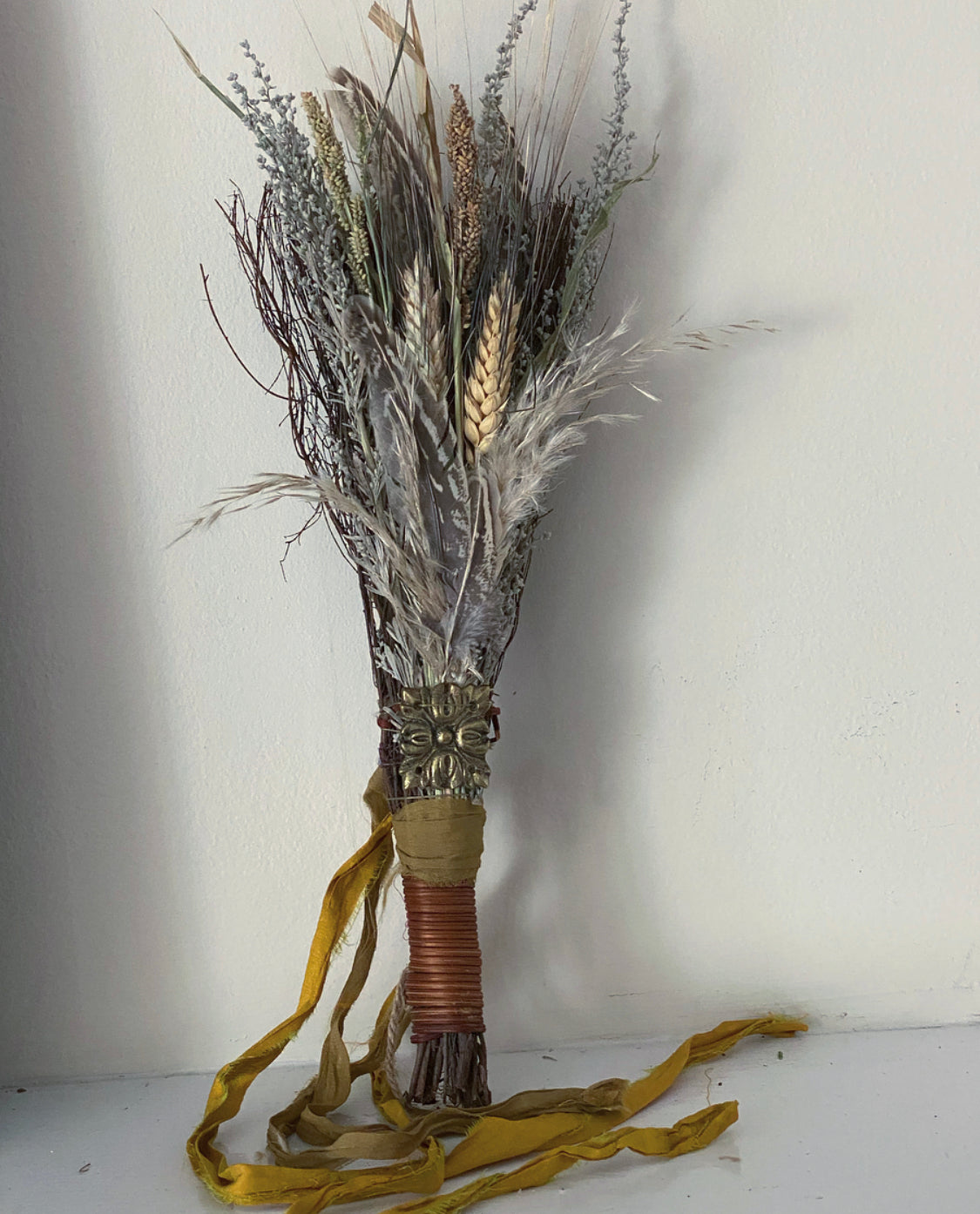 a dried floral arrangement for rustic decor brown and warm earthy colors with silk ribbons and a brass charm 