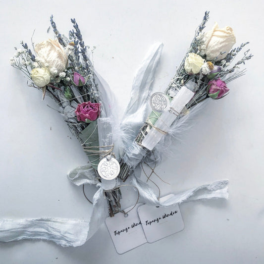 spiritual smoke cleansing sticks made for rustic weddings and events. Made with White and pink roses, lavender, white daisies, chamomile blue sage is sustainably harvested and handpicked in California . Includes a large selenite healing crystal and silk ribbons