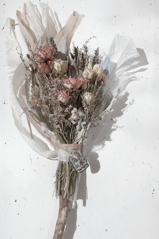 A dried floral bouquet featuring a variety of herbs and small flowers, tied with silk ribbons, and presented with a card.